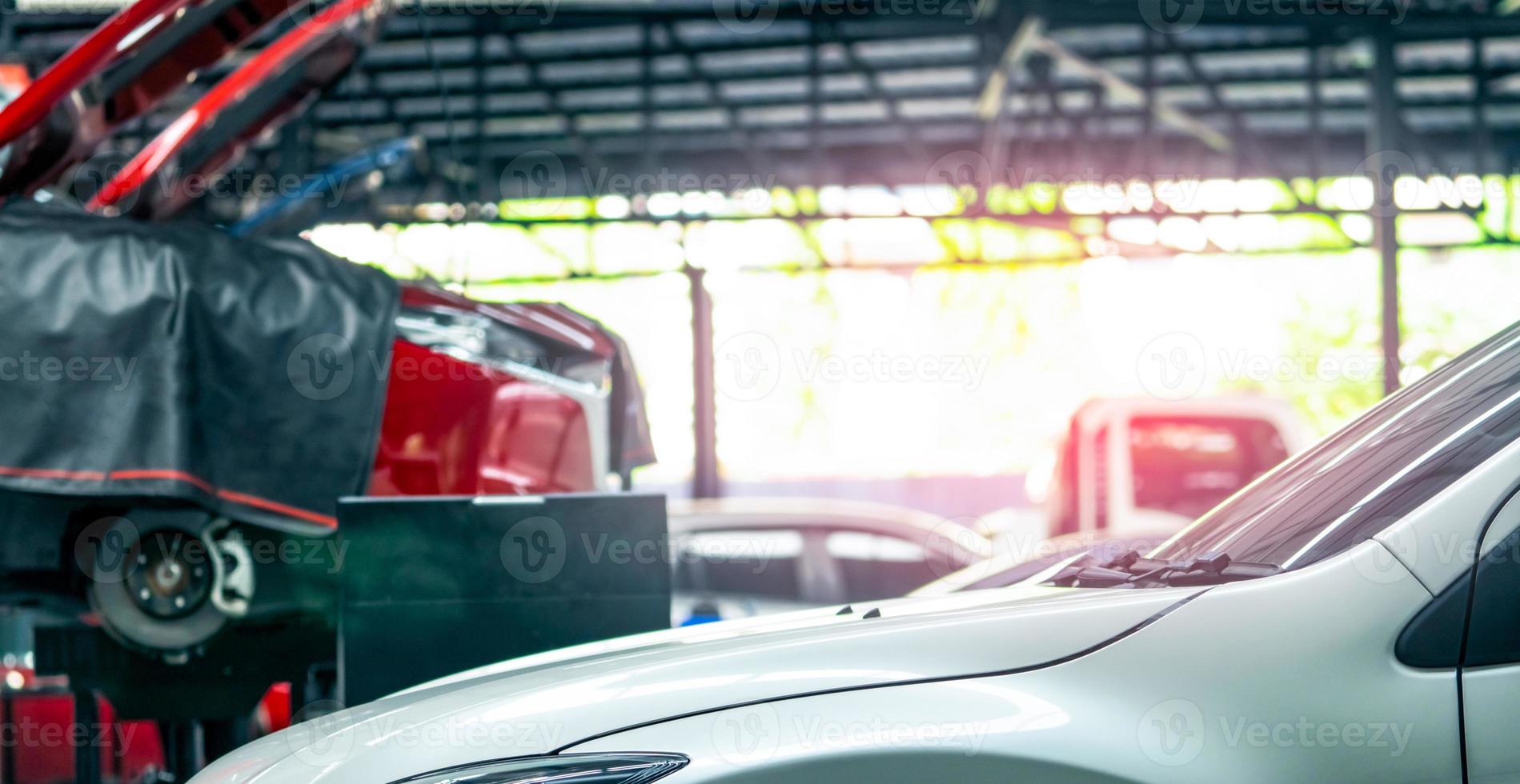 officina di riparazione auto. auto bianca su suv rosso sfocato sollevata in garage per servizio di riparazione e manutenzione. check-up auto presso stazione di servizio. carrozzeria sollevata in officina. concetto di lista di controllo per la manutenzione dell'auto. foto