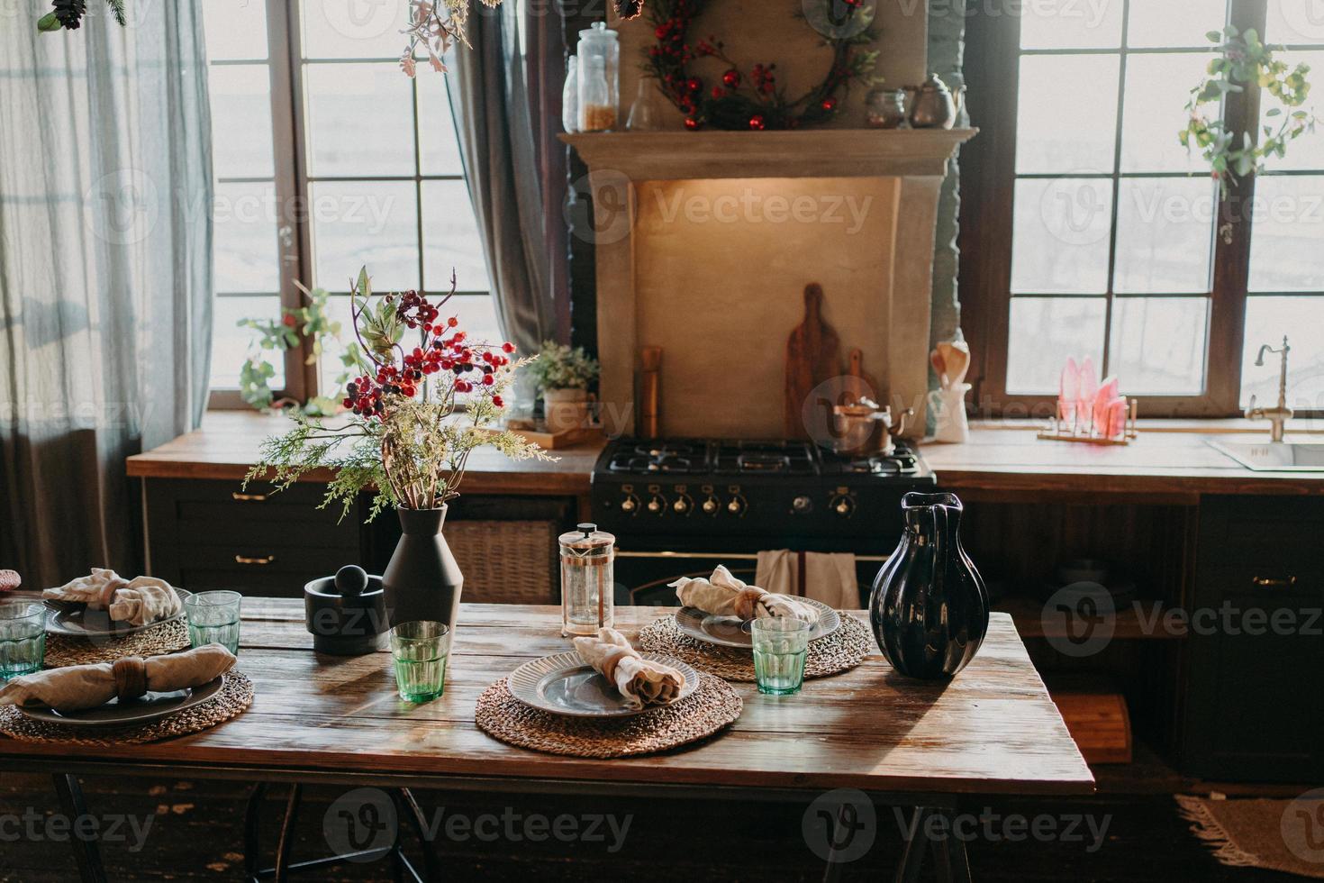 interno della cucina. servito tavolo da pranzo con piatti bicchieri decoro floreale. posate e bicchieri. preparazione per la cena festiva. apparecchiare la tavola per la cena in famiglia foto