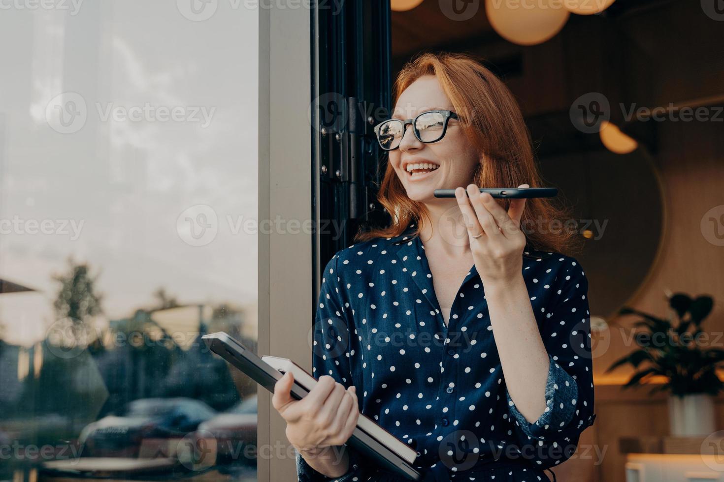 la donna con i capelli rossi tiene i colloqui telefonici in vivavoce con un amico fa il riconoscimento vocale foto