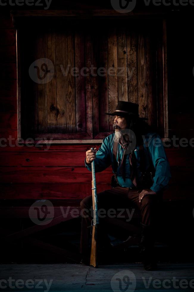 il cowboy anziano sta puntando il fucile verso l'attaccante, mentre la sorveglianza di sicurezza nelle aree agricole rurali foto