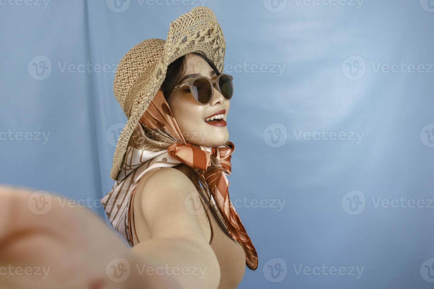 concetto di viaggio di una giovane donna asiatica che si fa un selfie isolato da uno sfondo blu foto