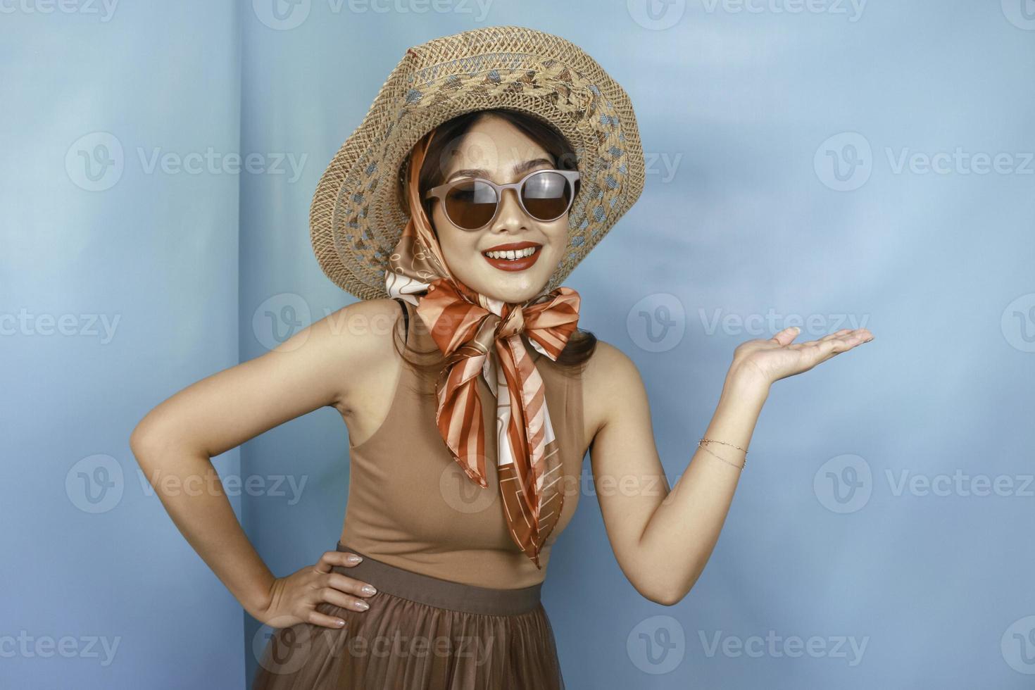 giovane donna asiatica felice isolata da uno sfondo blu che indica lo spazio della copia sul lato. foto