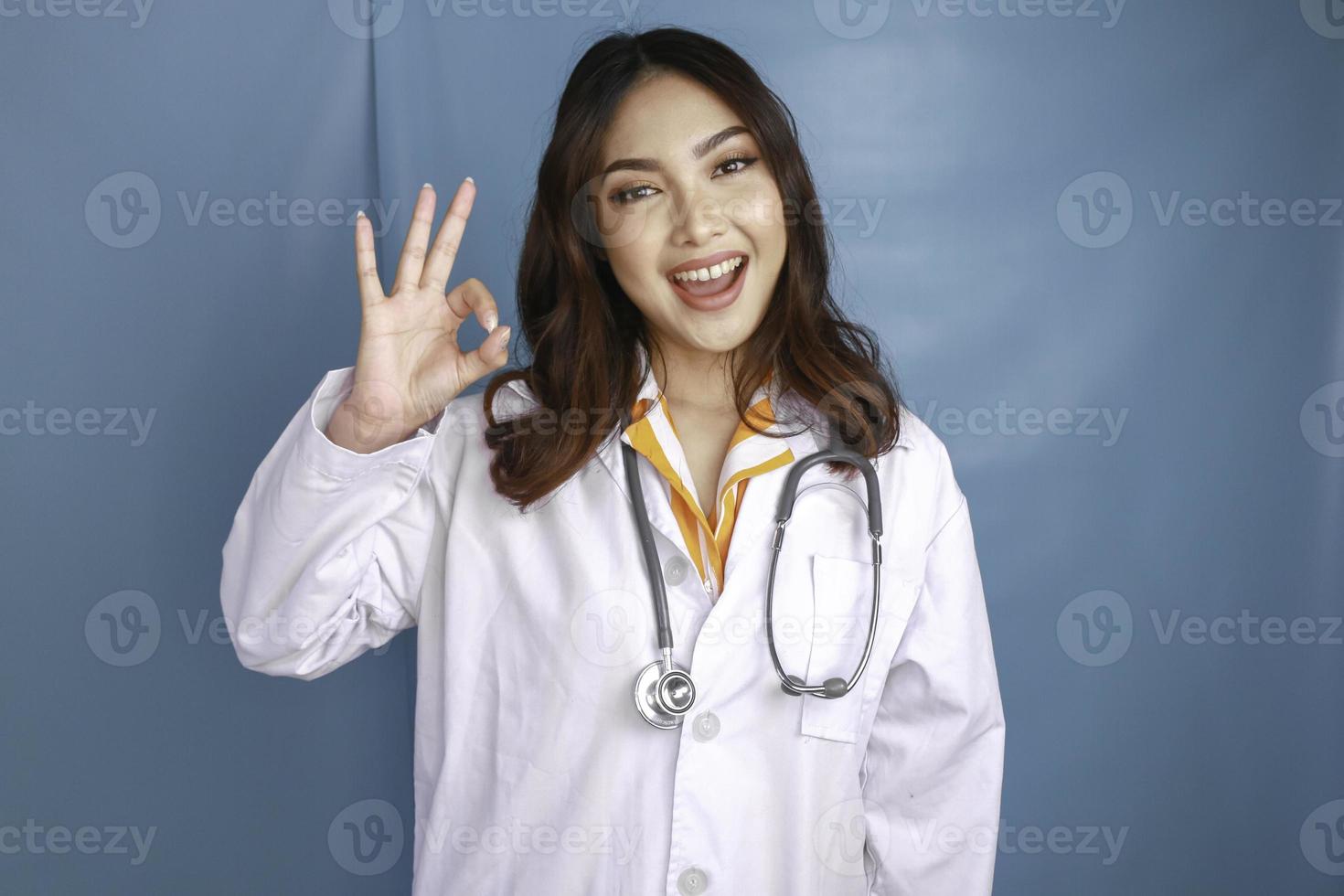 il medico della giovane donna asiatica sta sorridendo e mostra il segno giusto. foto