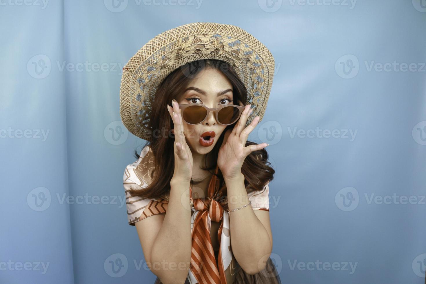giovane donna asiatica scioccata e isolata da uno sfondo blu. foto