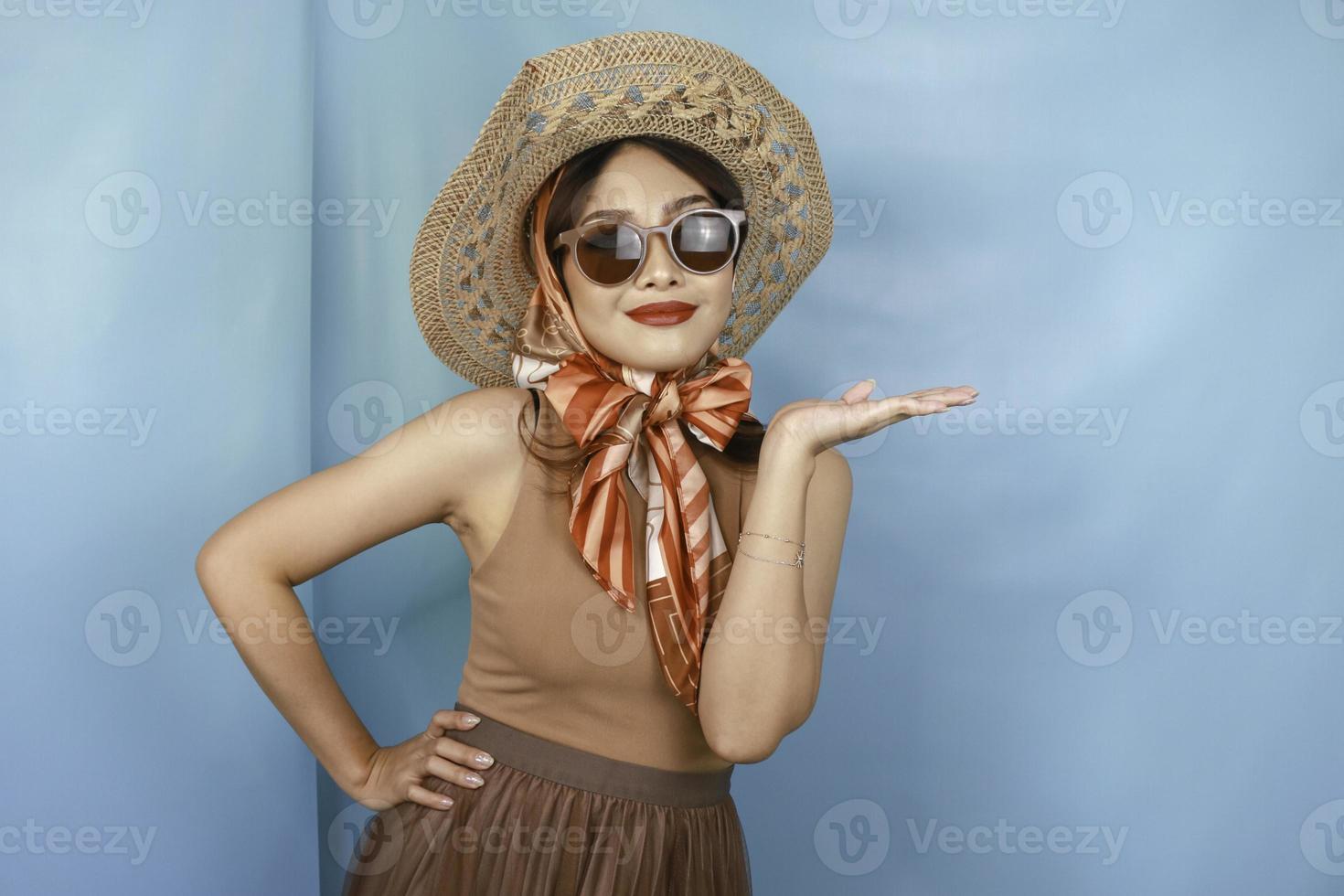 giovane donna asiatica felice isolata da uno sfondo blu che indica lo spazio della copia sul lato. foto