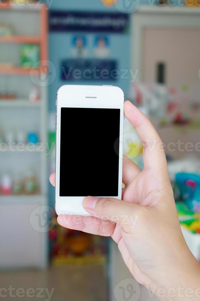 mano che tiene smart phone in farmacia foto