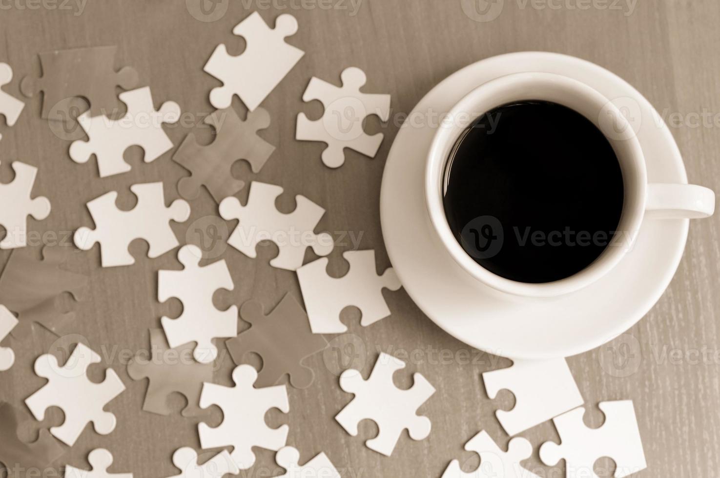 tazza di caffè e pezzi del puzzle sul tavolo foto
