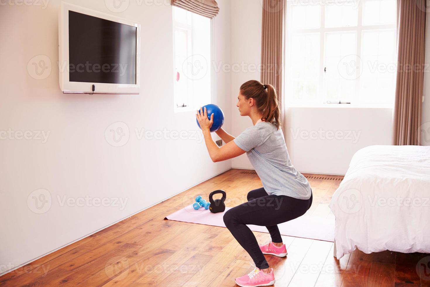 donna che lavora al fitness dvd in tv in camera da letto foto