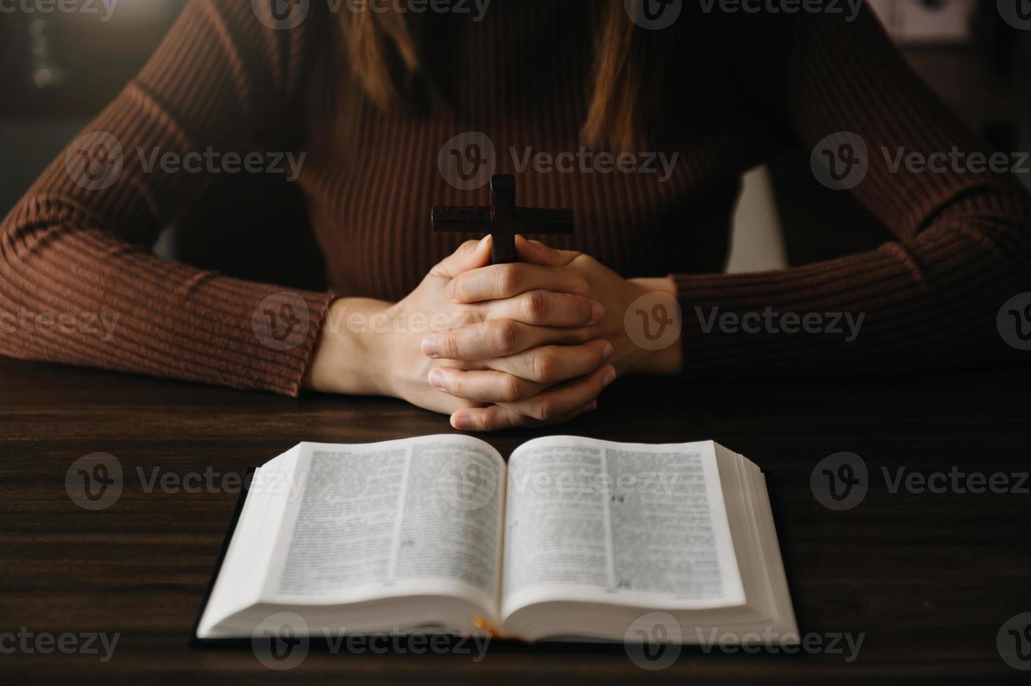 donna seduta e studiare le scritture.la croce di legno nelle mani. concetti di educazione cristiana le sacre scritture si aprono e pregano Dio. foto