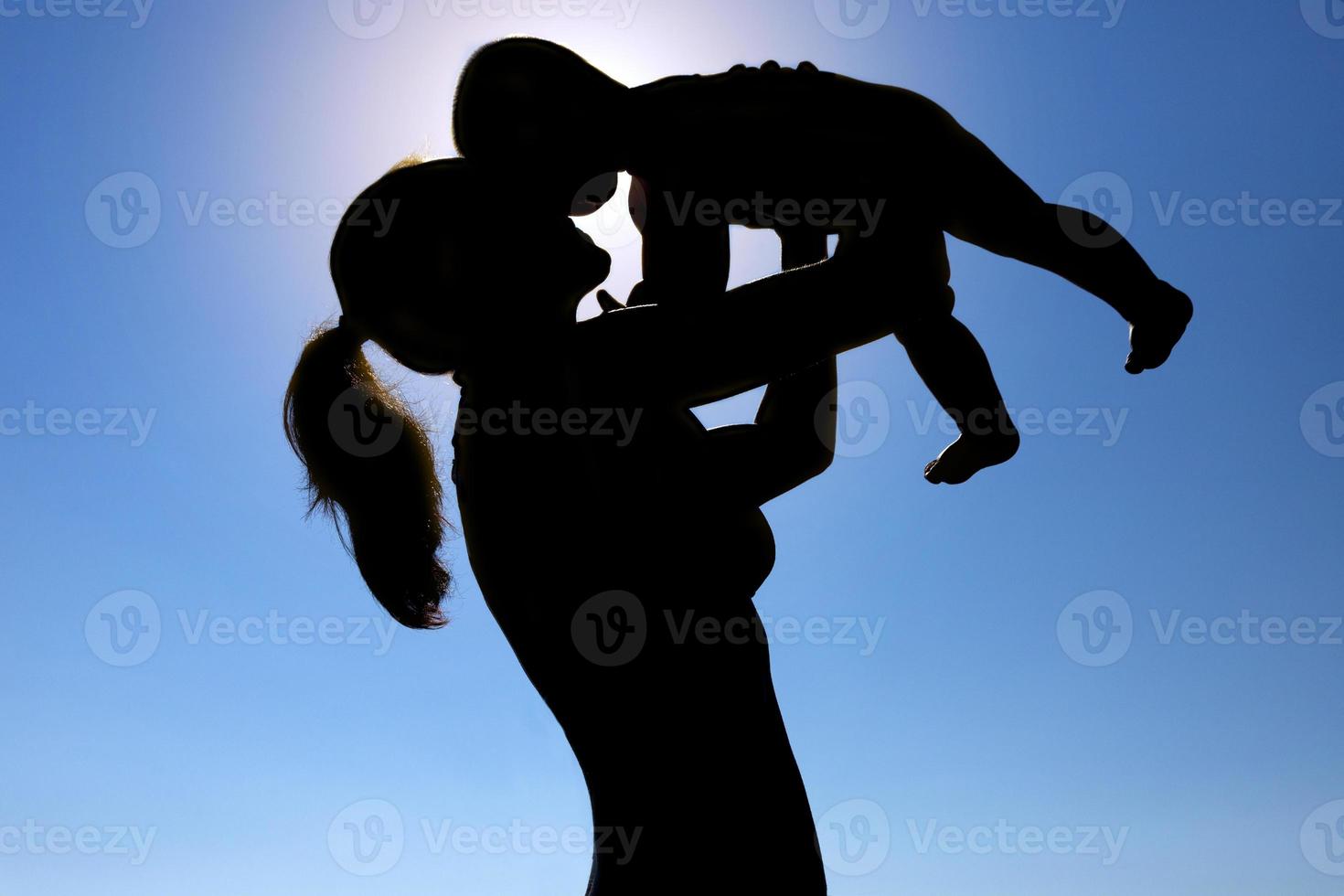 una giovane ragazza tiene in braccio un bambino contro il sole. fotografia di silhouette. foto