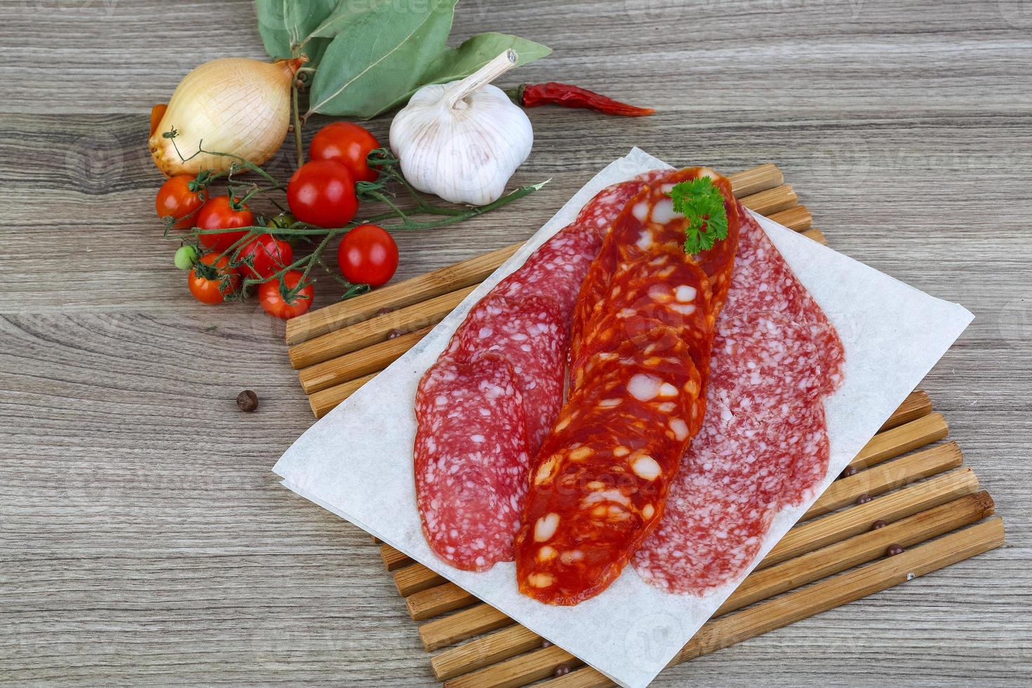 salsiccia di salame sul piatto di legno e sullo sfondo di legno foto