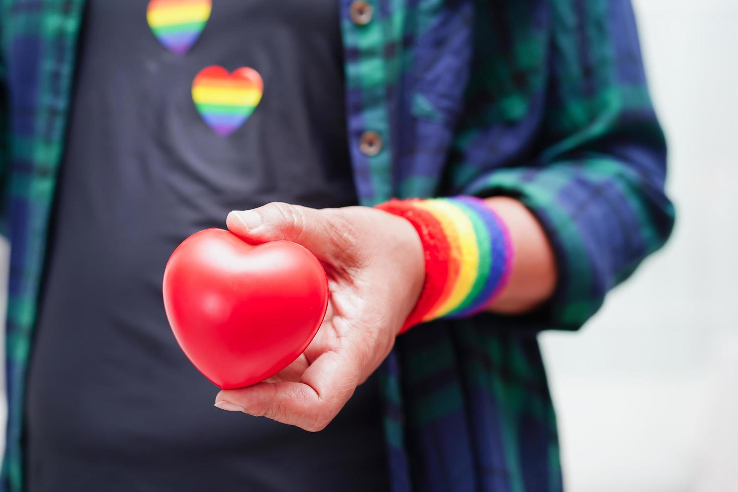 donna asiatica che tiene un hert rosso con bandiera arcobaleno, diritti dei simboli lgbt e uguaglianza di genere, mese dell'orgoglio lgbt a giugno. foto