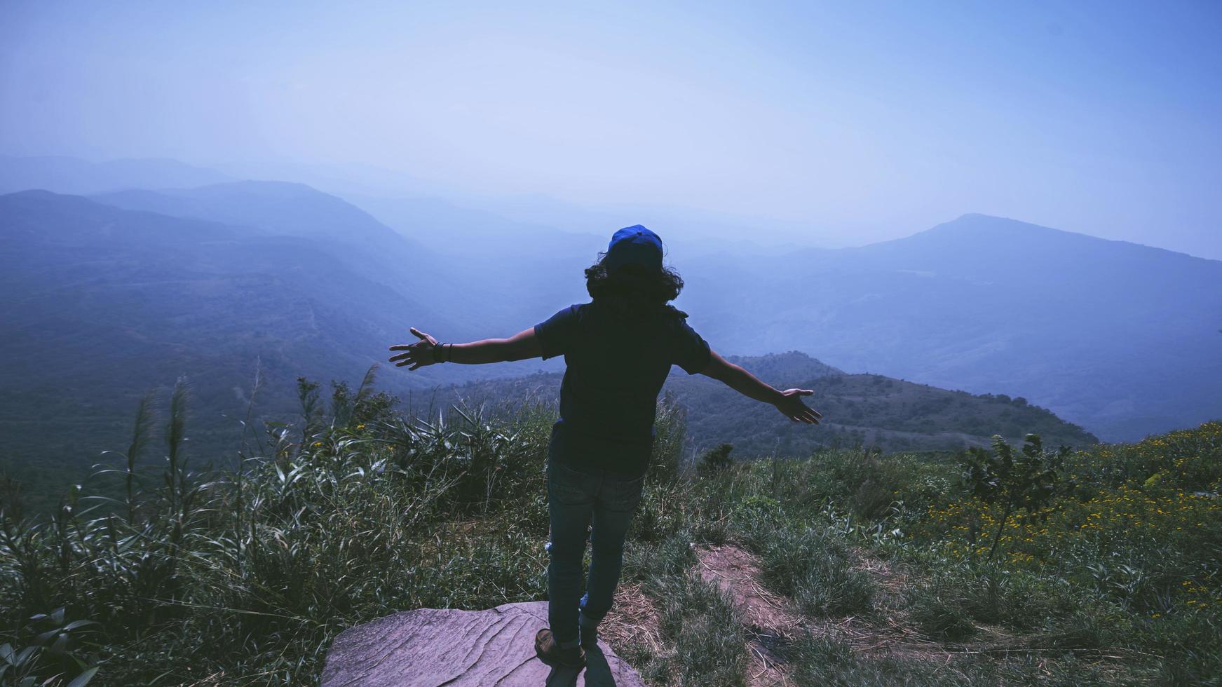 il viaggio dell'uomo asiatico si rilassa durante le vacanze. stare in piedi e guardare il paesaggio sulla montagna. parco di montagna felicemente. in Thailandia foto