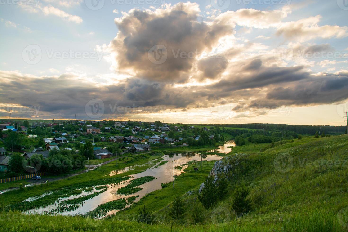 un villaggio sulla riva del fiume con erba verde brillante e un bel cielo. foto