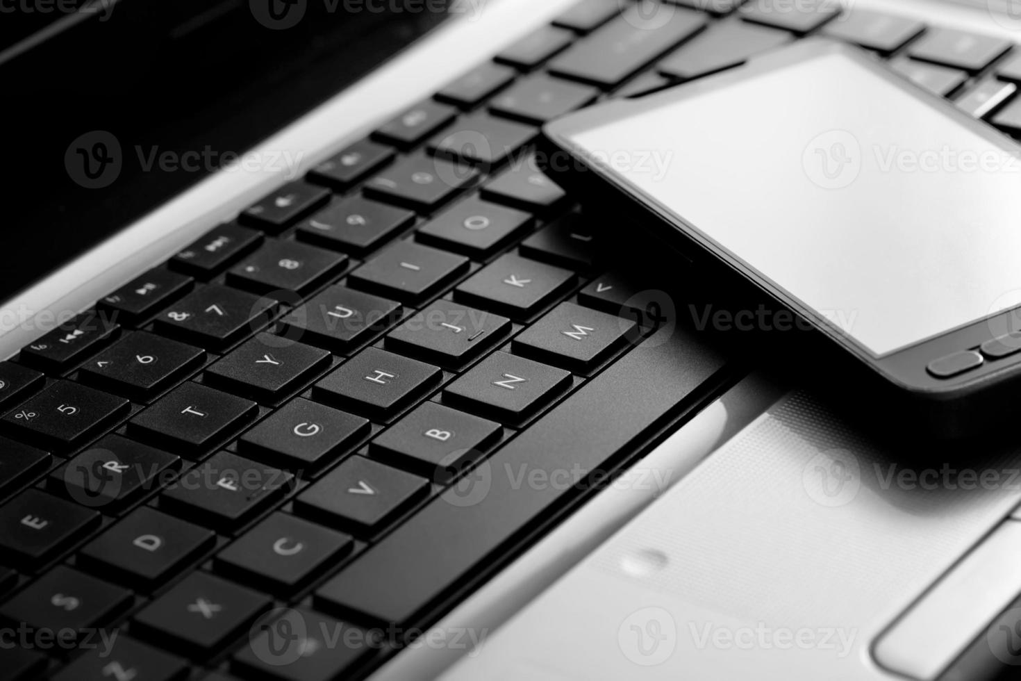 uno smartphone si trova sulla tastiera di un laptop foto