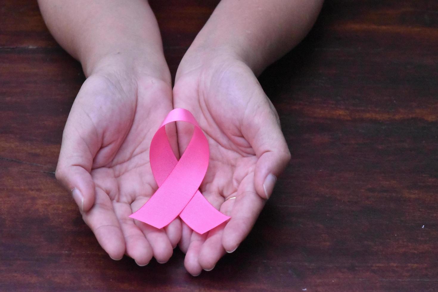 il nastro rosa in mano, simbolo della campagna mondiale contro il cancro al seno delle donne. foto