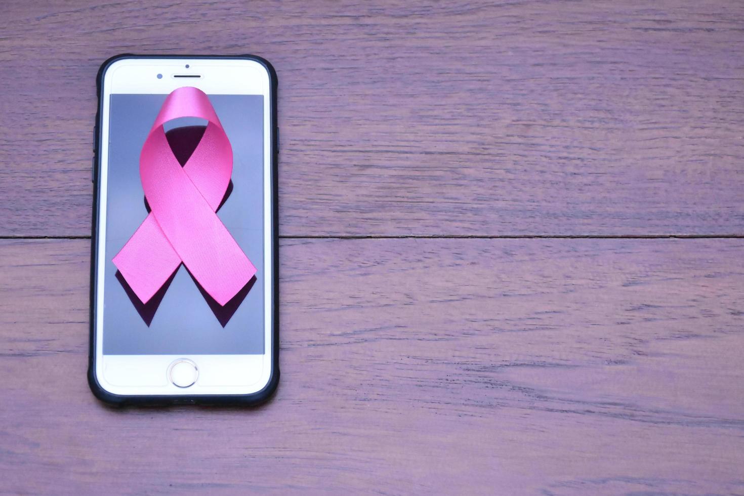 nastro rosa sul tavolo con il telefono cellulare. concetto per protestare e sostenere il cancro al seno nella donna. foto