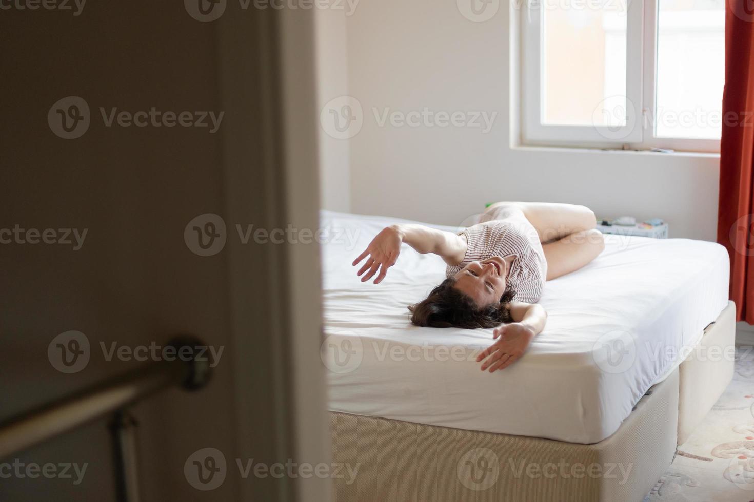 la ragazza si sdraia sul letto e si allunga, la donna si sveglia foto