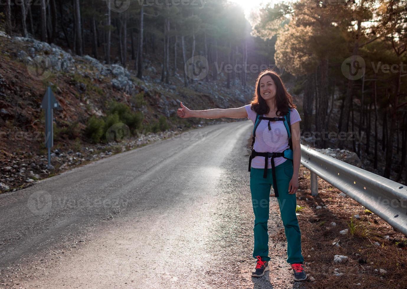 la ragazza si ferma sulla strada e ferma l'auto, facendo l'autostop foto