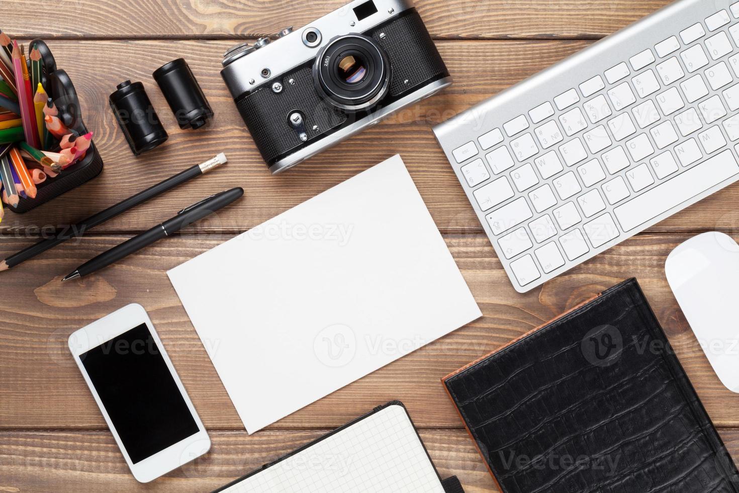 scrivania con forniture, macchina fotografica e scheda vuota foto