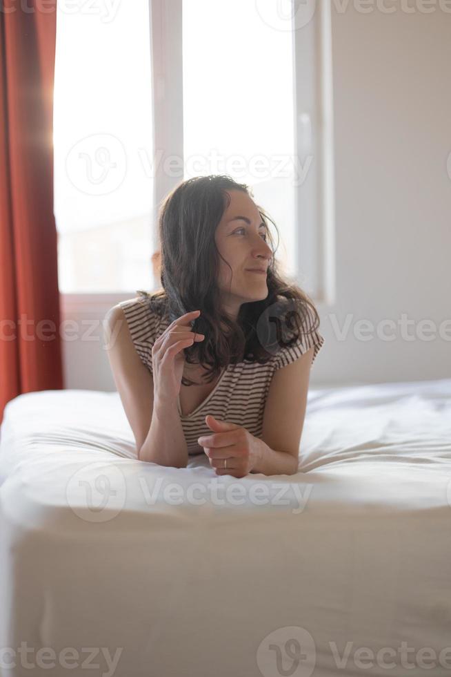 ragazza si trova sul letto, donna sorridente in camera da letto foto