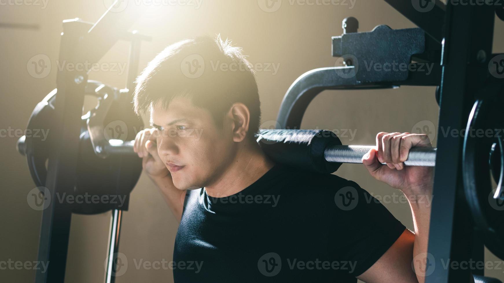 uomo che si esercita con il bilanciere, allenamento con i pesi che costruisce la forza del corpo in palestra al sole del mattino. foto