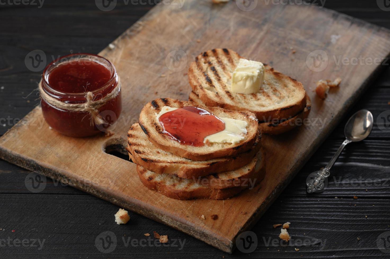 pane tostato con marmellata di fragole fatta in casa e su tavola rustica con burro per colazione o brunch. foto