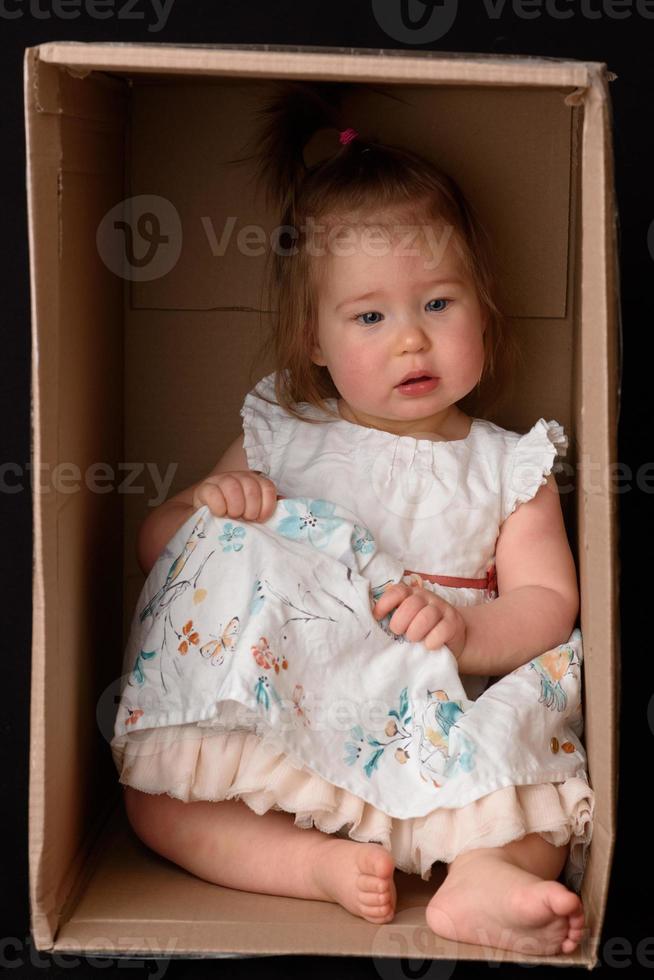 felice bambina seduta in una scatola di cartone e divertirsi foto