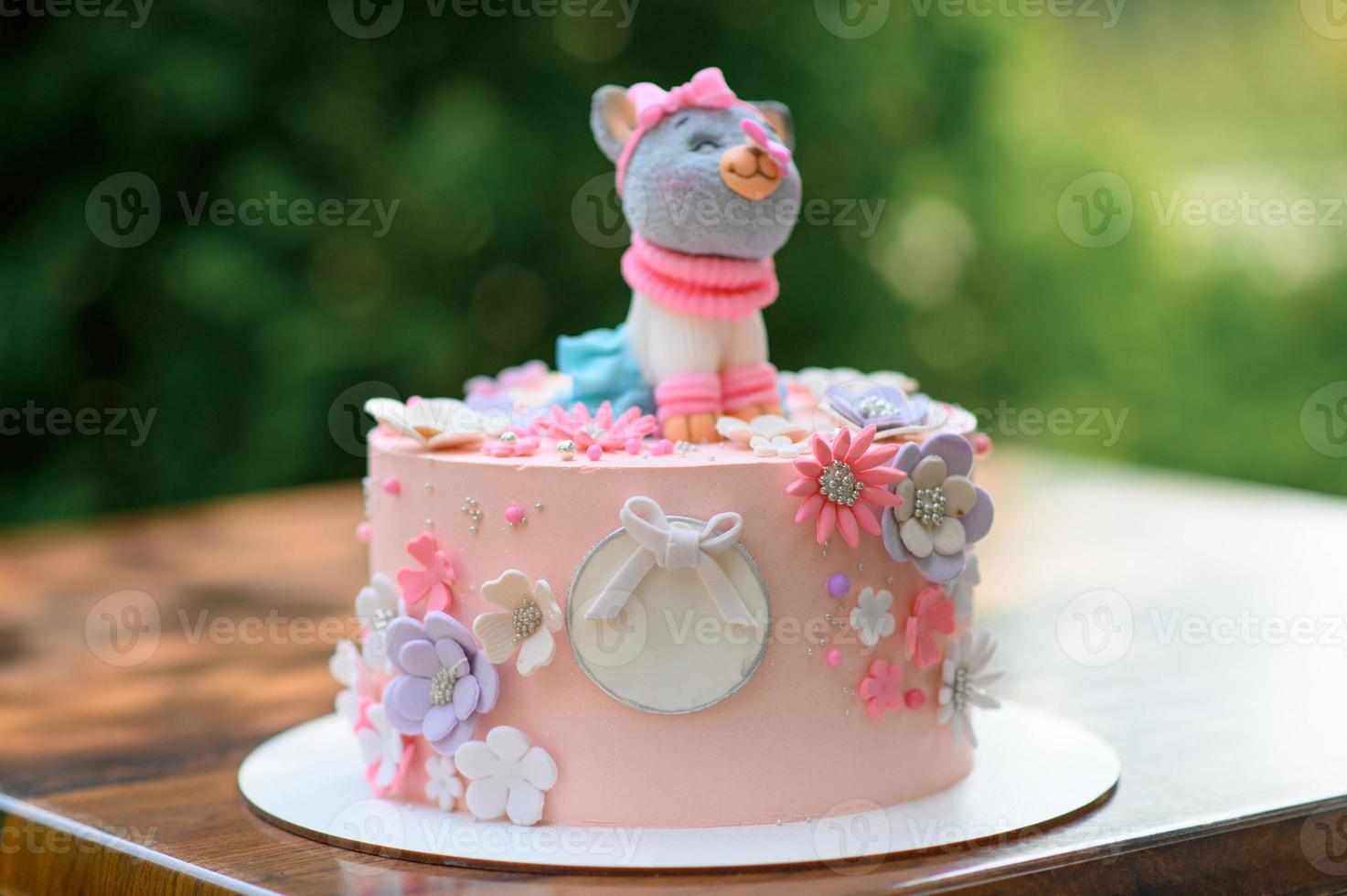 torta rosa festiva con un gatto in cima. foto