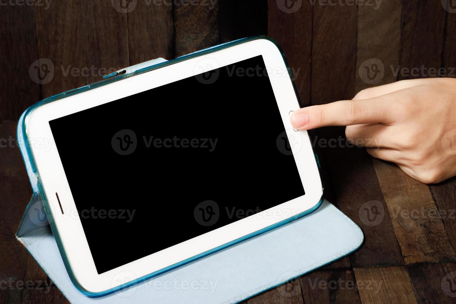 mano che tiene un tablet su fondo in legno foto