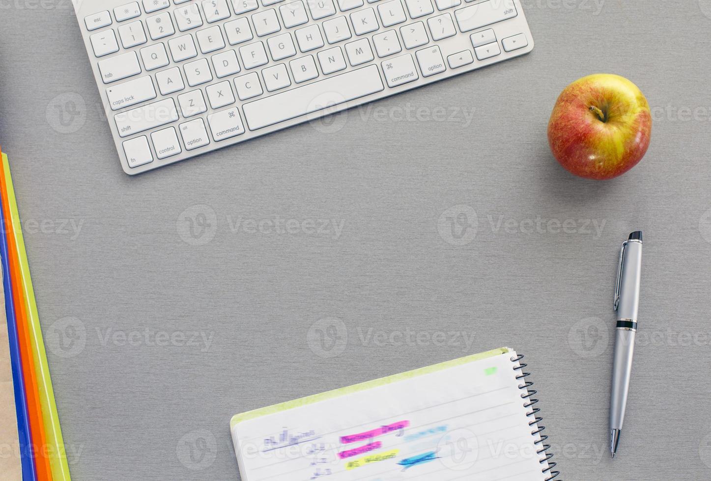 spazio di lavoro in ufficio sulla scrivania grigia con mela rossa foto
