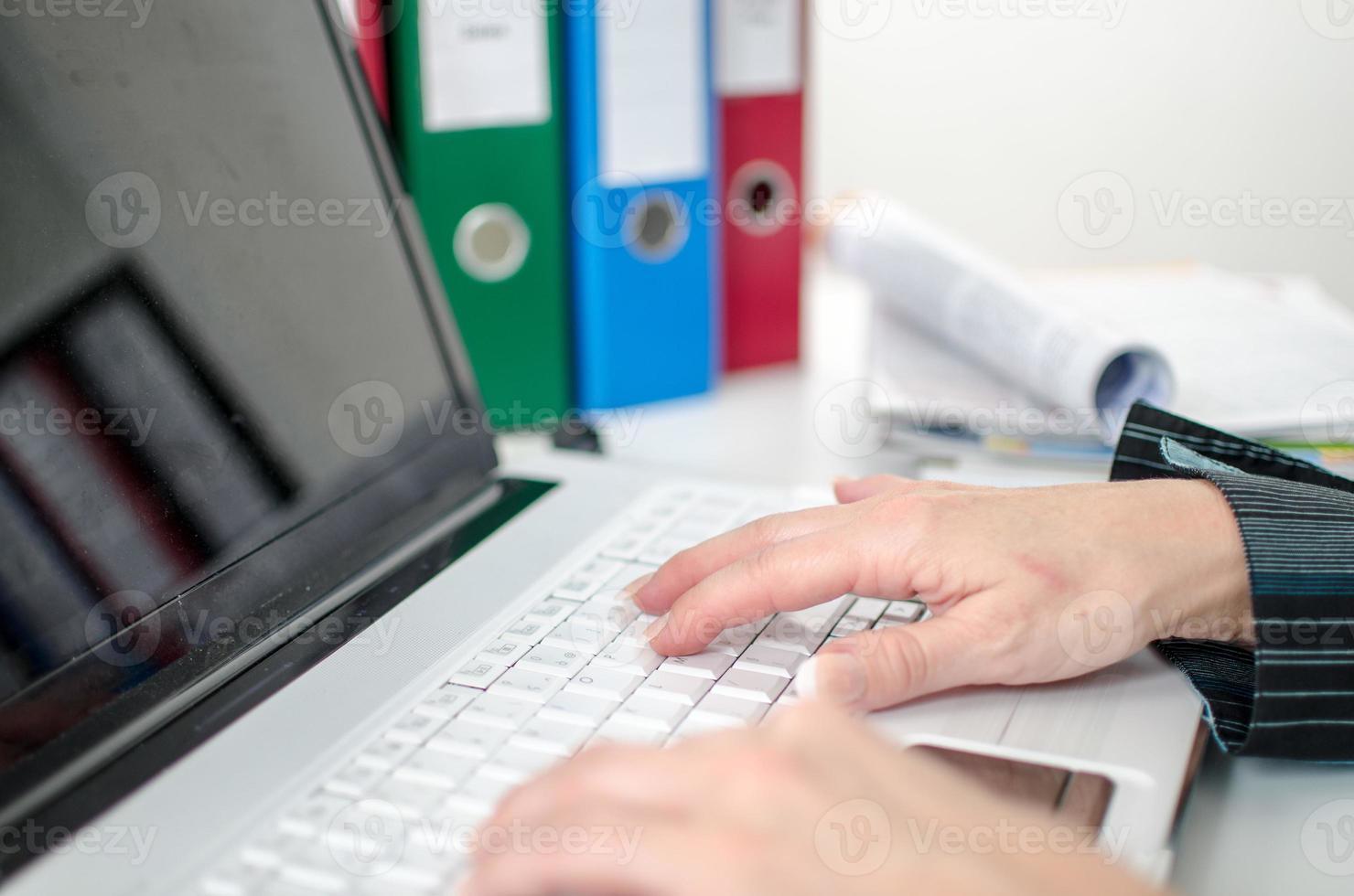 mani che digitano sulla tastiera di un computer portatile foto