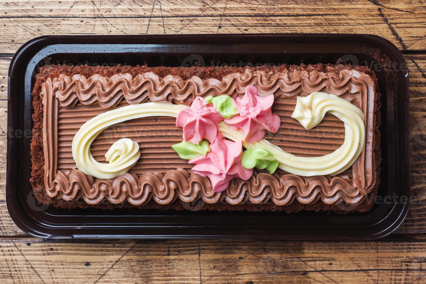 torta rettangolare al cioccolato decorata con rose color crema. il cibo dolce è un'attività di pasticceria. vista dall'alto foto