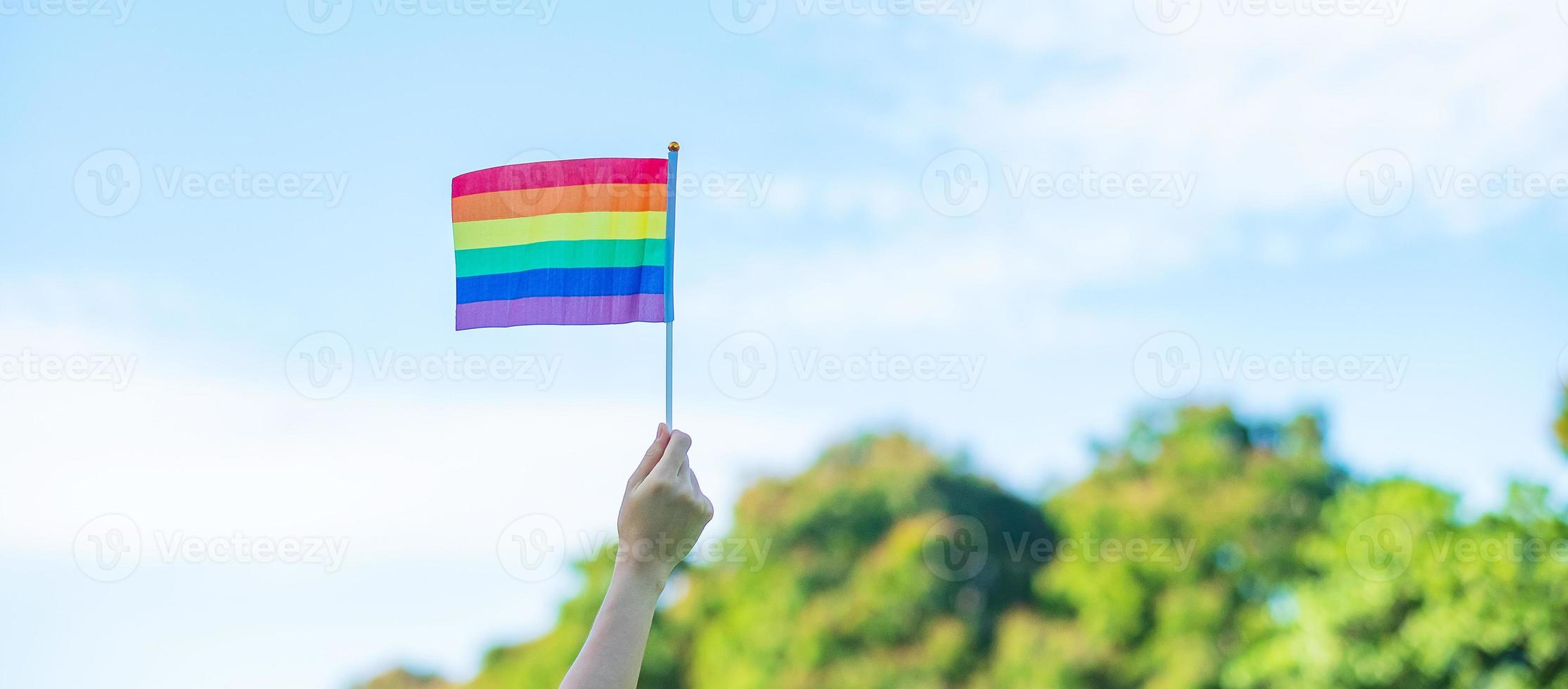 mani che mostrano la bandiera arcobaleno lgbtq sullo sfondo della natura. sostenere la comunità lesbica, gay, bisessuale, transgender e queer e il concetto di mese dell'orgoglio foto