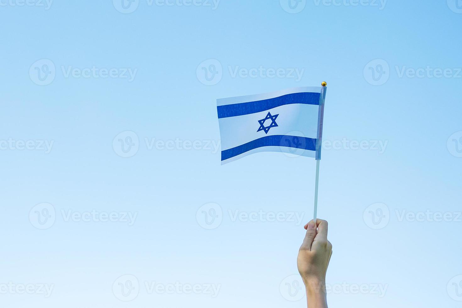 mano che tiene la bandiera israeliana sullo sfondo della natura. giorno dell'indipendenza di israele e concetti di celebrazione felice foto