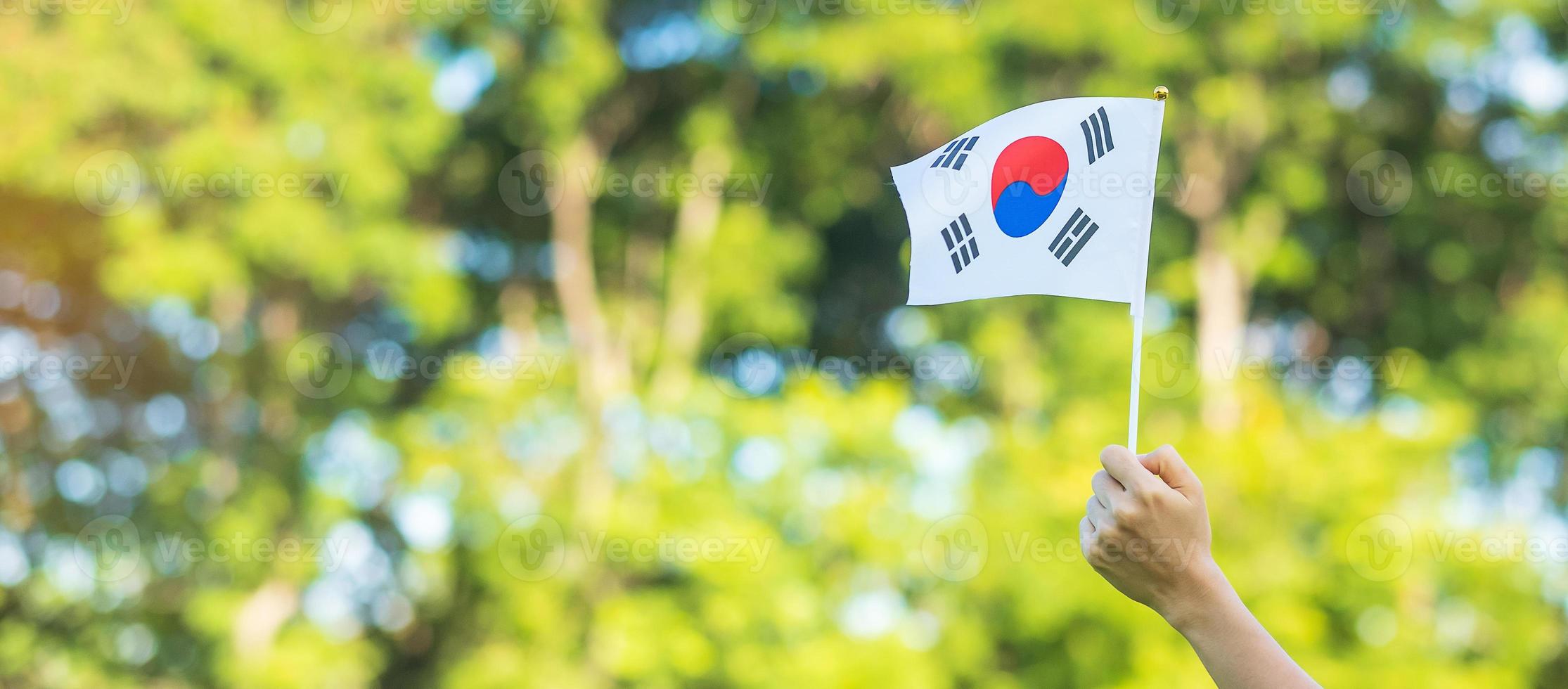 mano che tiene la bandiera della Corea sullo sfondo della natura. fondazione nazionale, gaecheonjeol, festa nazionale della nazione, giorno della liberazione nazionale della Corea e concetti di felice celebrazione foto