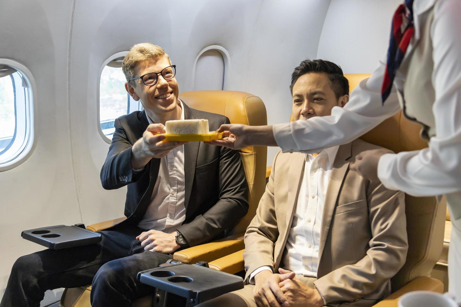 l'assistente di volo sta servendo cibo al cliente per il pasto in volo, il viaggio aereo e il concetto di trasporto foto