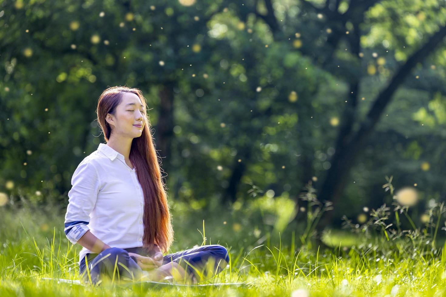 donna che pratica in modo rilassante la meditazione nella foresta per raggiungere la felicità dalla pace interiore saggezza per mente e anima sane nella luce della sera con sfondo bokeh di insetti moscerini e mosche di fuoco foto