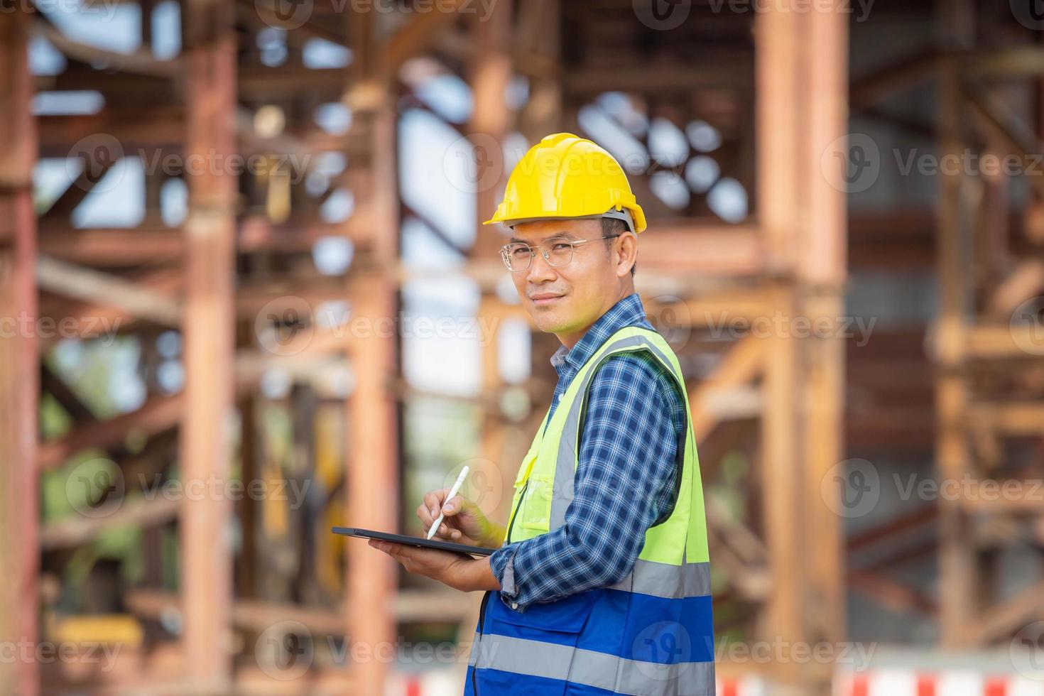 uomo in elmetto protettivo con tavoletta digitale al cantiere dell'infrastruttura, progetto di controllo dell'ingegnere in cantiere foto