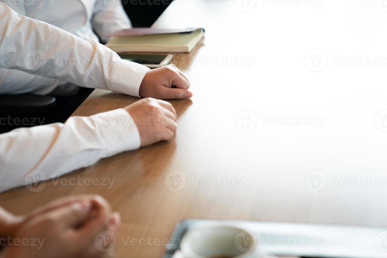 vicino la mano degli uomini d'affari, stanno parlando insieme sul tavolo di legno al pomeriggio. foto