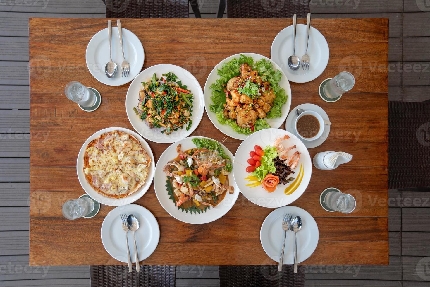 set da pranzo applicato tailandese come frutti di mare fritti con salsa, pizza, insalata di salmone e gamberi fritti sul tavolo di legno dall'angolo di vista dall'alto ed è pronto da mangiare. foto