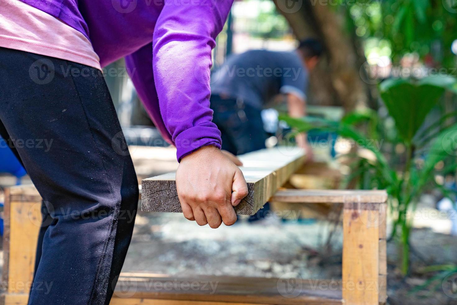 lavoratore strofina il grande piatto di legno lungo con la lucidatrice in giardino. foto
