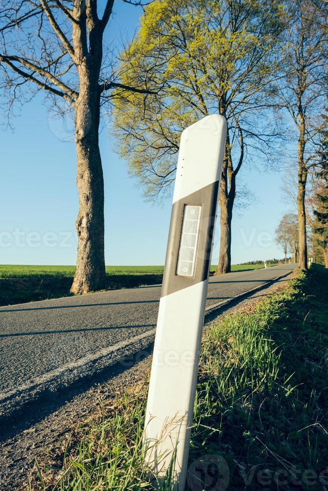 delineatore su una strada di campagna vuota foto