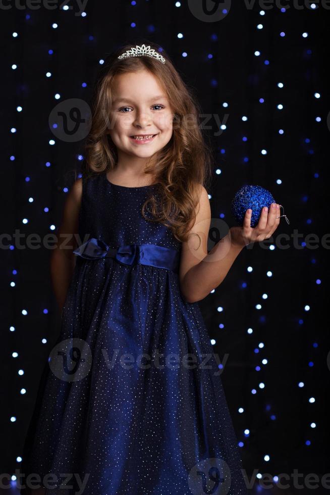 la ragazza graziosa del bambino sta tenendo la palla blu di natale foto