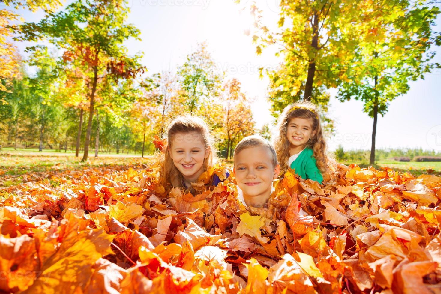 bambini che si divertono in posa a terra con foglie foto