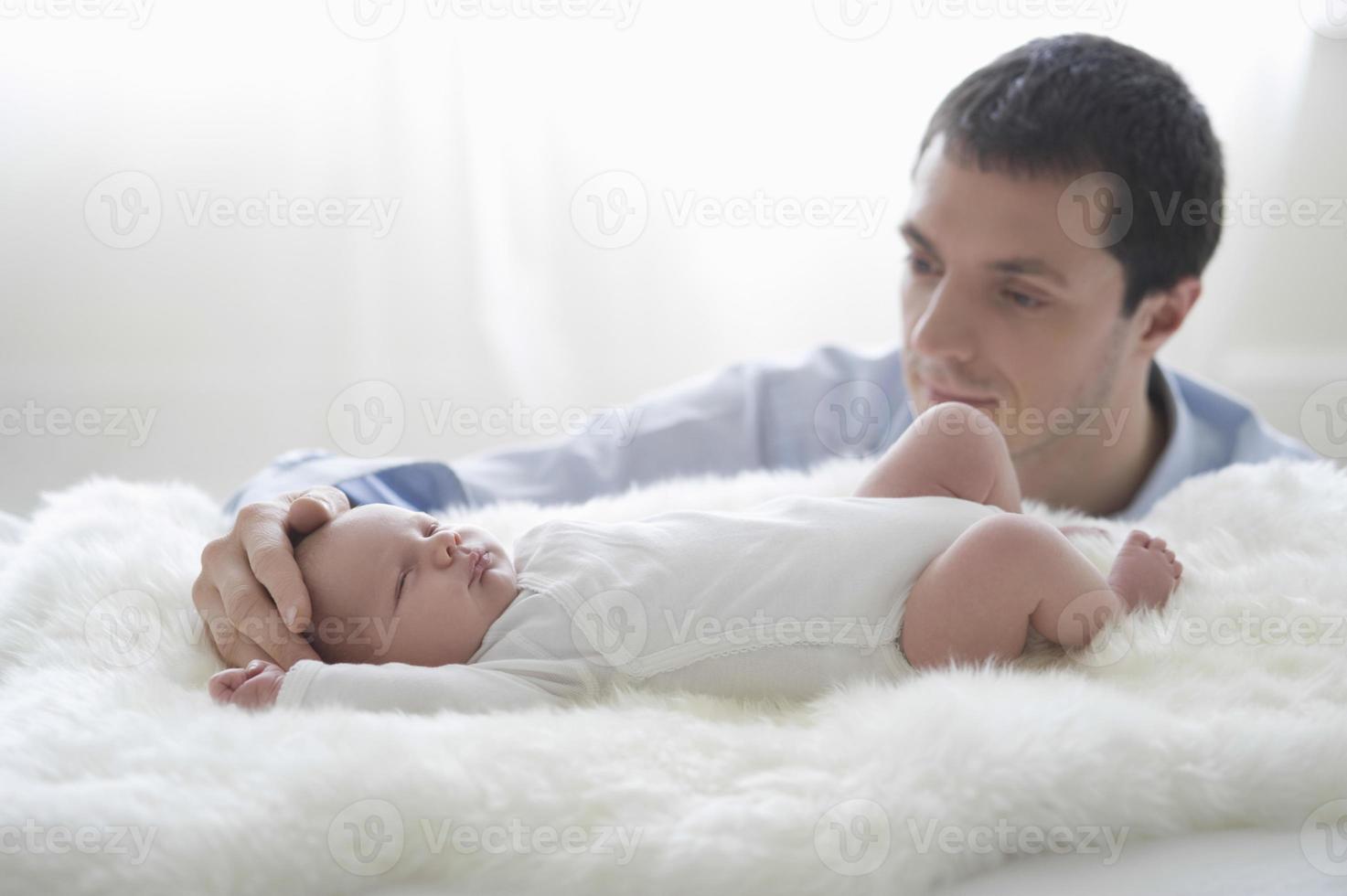 padre che accarezza la testa del neonato foto