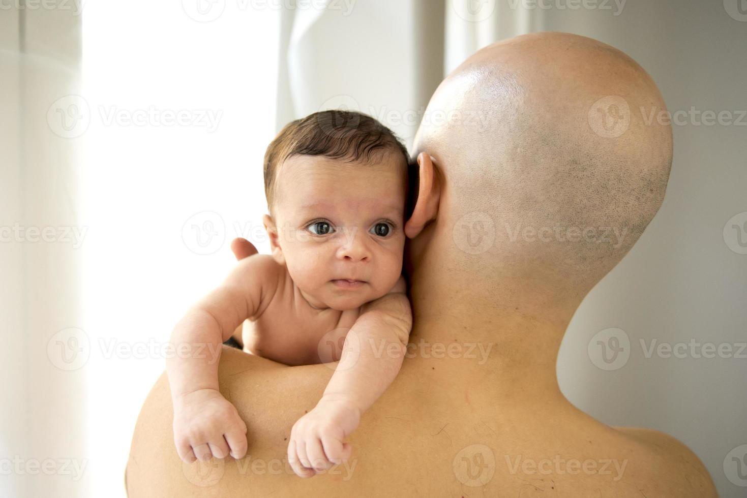 neonato che piange sopra la spalla di suo padre foto
