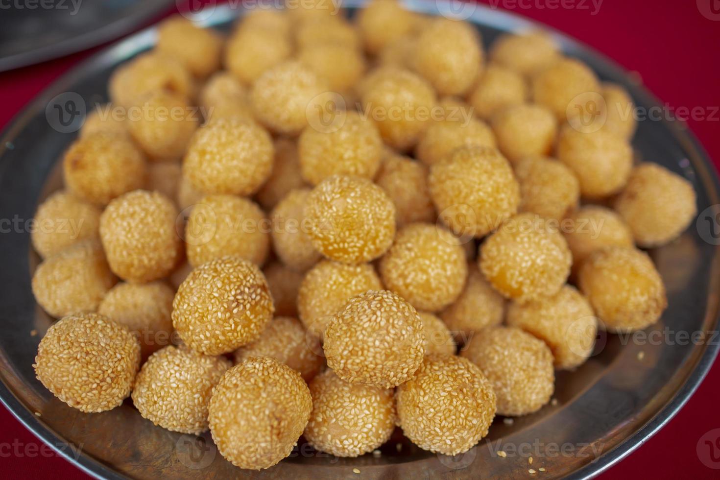 un piatto pieno di palline di semi di sesamo pronte per essere mangiate. è ripieno di pasta di fagioli rossi e popolare in Malesia foto