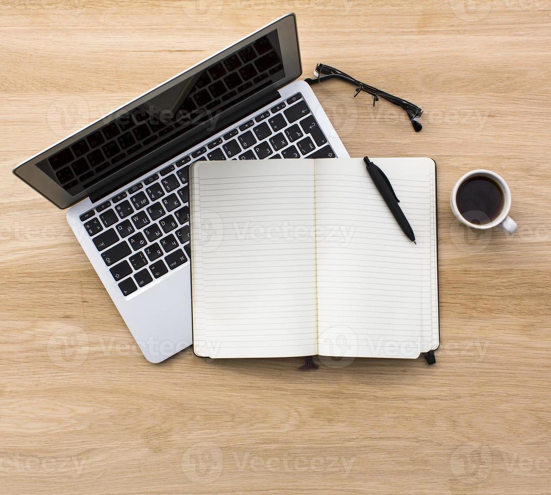 laptop, notebook con penna, occhiali da vista e tazza di caffè foto