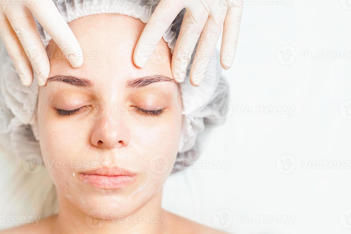 donna nel salone spa ricevendo un trattamento viso con crema viso foto